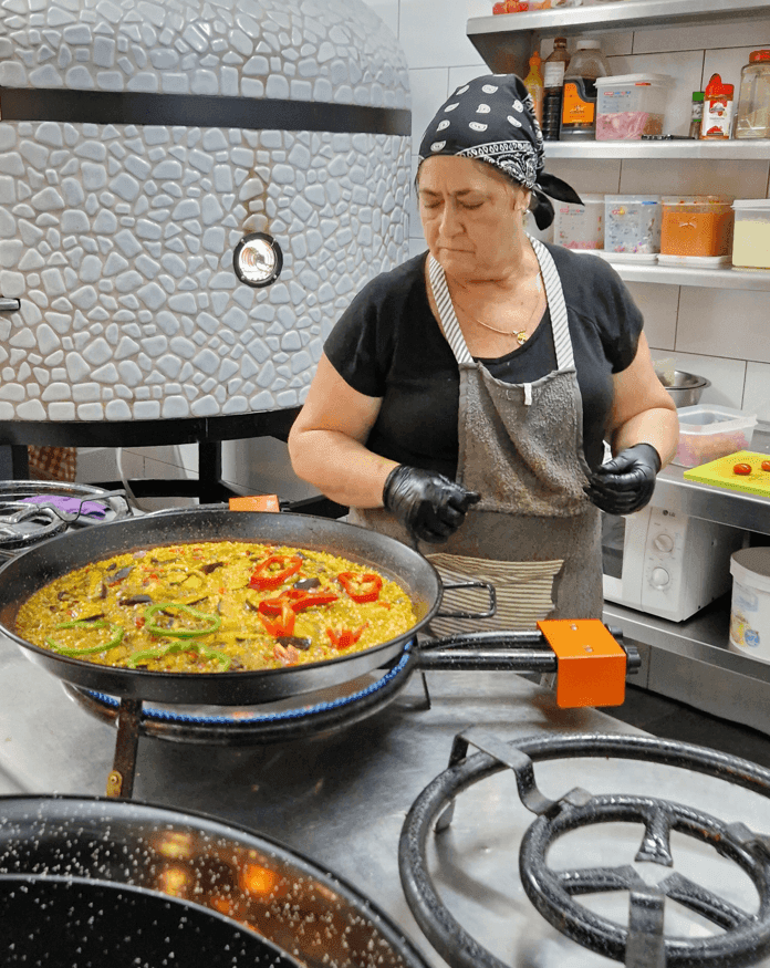 Cocinera haciendo una paella el el restaurante La Paella de los Abrigos