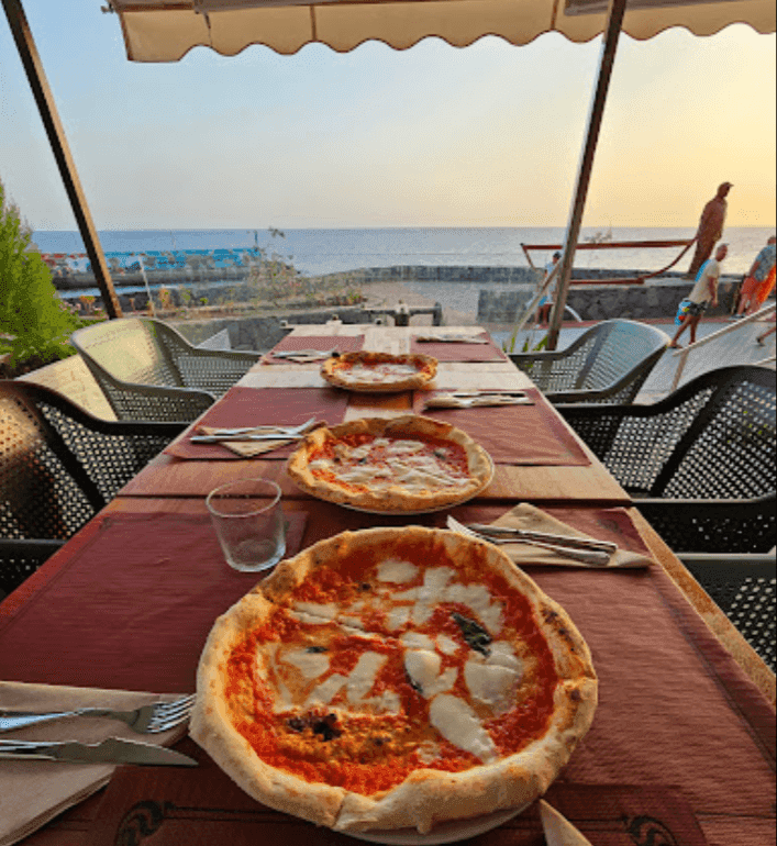 Imagen de una mesa con 3 pizzas Napolitanas en la terraza del Restaurante La Paella de Los Abrigos Tenerife